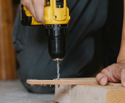 Unrecognizable man drilling hole in wooden blank