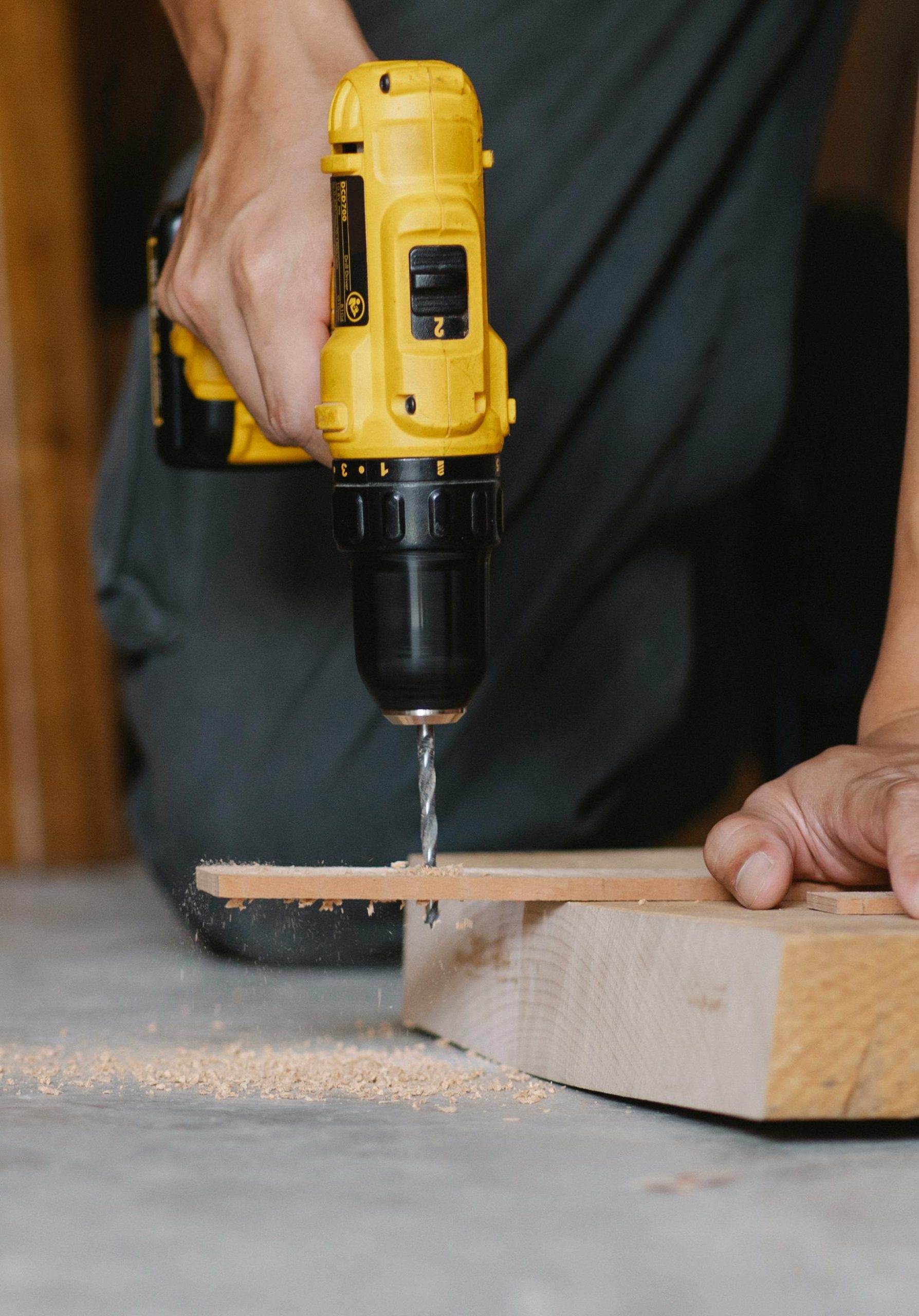 Unrecognizable man drilling hole in wooden blank